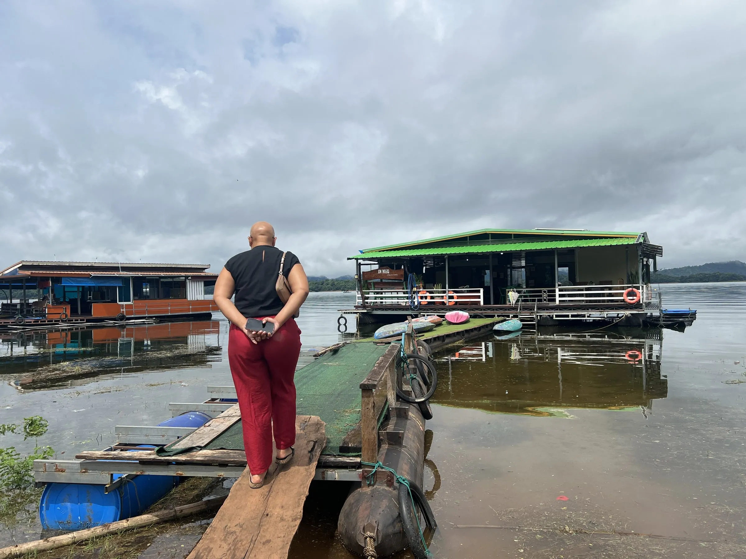 A visitor walking down the wooden gangway onto the moored raft house.