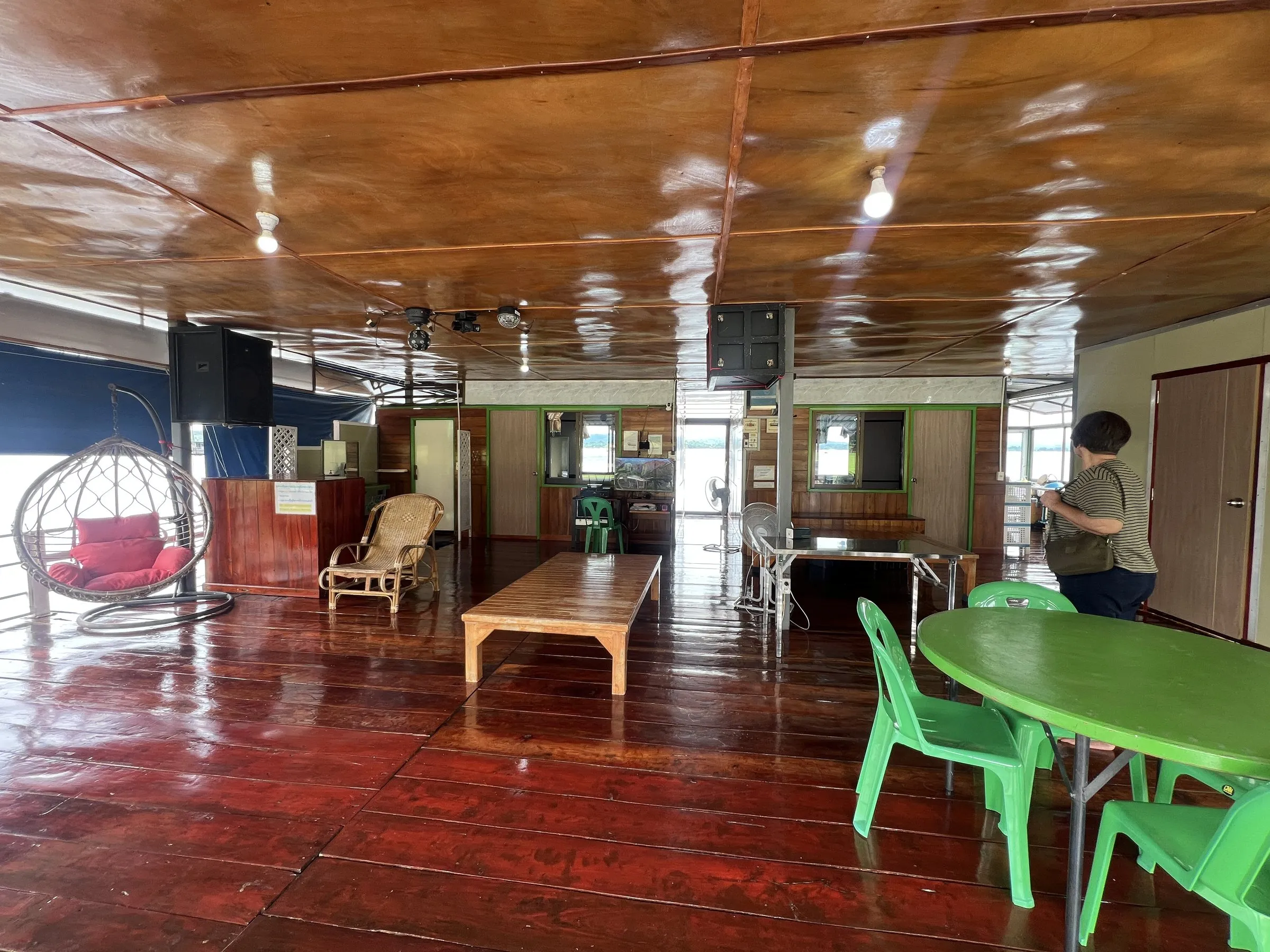 The open communal deck with hanging chairs, a table and windows onto the lake.